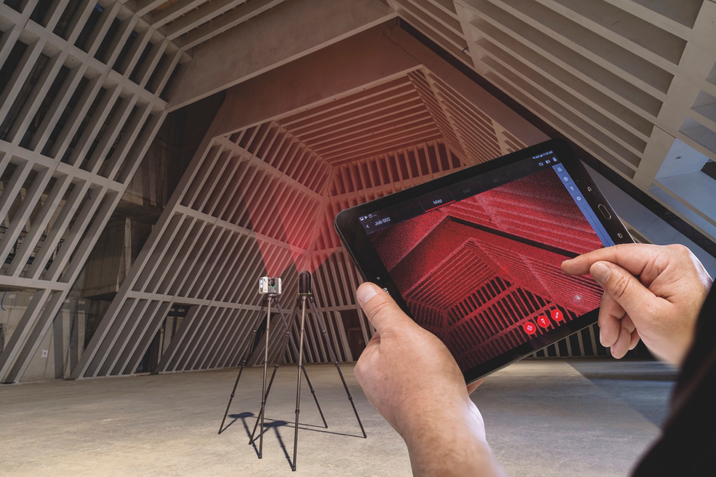 Tablette avec nuage de points 3D rouge de chevrons en bois tenue devant un scanner laser Leica dans un grand hall en béton avec structure de toit triangulaire